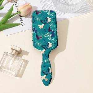 Détail d'une brosse à cheveux plate sarcelle avec motifs papillons et décor tulipe