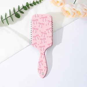 Détail de la brosse à cheveux rose avec motifs nœuds papillons sur fond de fleurs