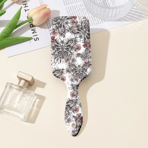 Détail de la brosse à cheveux à coussin d'air avec motifs papillons et fleurs élégants