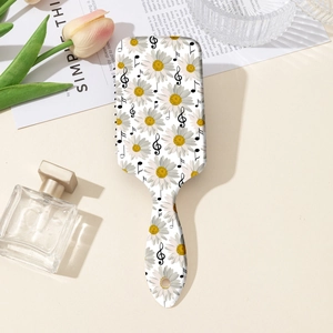 Detail view of floral print air cushion massage brush for detangling hair on white desk