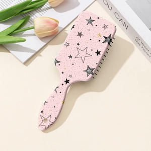 Vue détaillée d'une brosse à cheveux rose avec motif d'étoiles sur fond décoratif