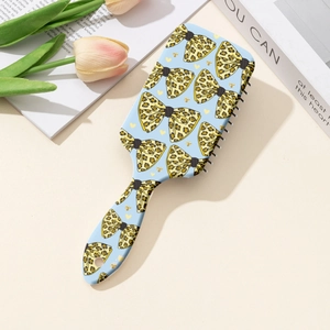 Detail view of leopard print bow hairbrush with black bristles on a cream desk