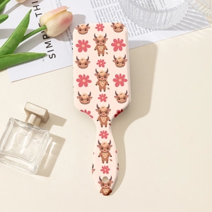 Détail de la brosse à cheveux avec imprimé vache des Highlands et motifs floraux doux