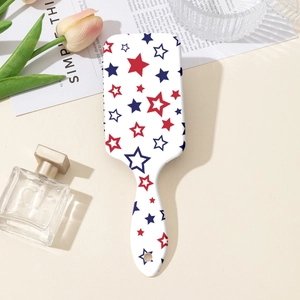 Detailed macro view of white hairbrush featuring red and blue star patterns on cushion