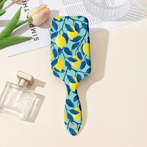 Vintage lemon print paddle hairbrush with ergonomic handle on a minimalist background