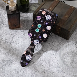 Detail of air cushion hairbrush with cosmic star patterns on a vintage wooden background