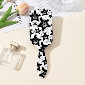 Detail of ergonomic paddle hair brush featuring a gothic black and white skull star pattern
