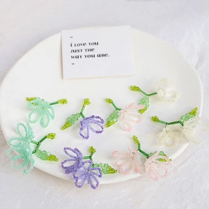 Macro detail of handmade beaded gradient flower charms in pastel colors on white plate