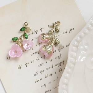 Dettaglio di ciondoli floreali in lega con petali rosa e foglie di cristallo verde