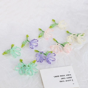 Macro shot of handmade beaded gradient flower charms in pastel mint green and purple