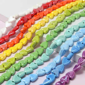 Vibrant rainbow heart ceramic beads on a display stand for DIY jewelry making and crafts
