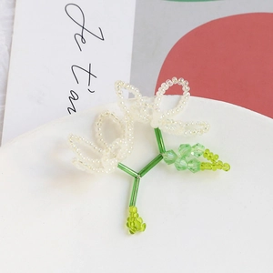 Detail of handmade beaded flower pendant with crystal petals and green stem accents