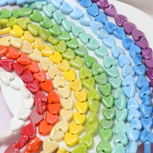 Macro shot of colorful ceramic heart beads arranged in a rainbow curve for DIY jewelry making