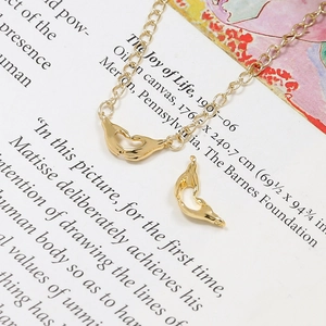 Détail du pendentif mains cœur en or et chaîne fine sur fond de livre vintage