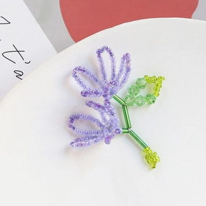 Macro shot of handcrafted beaded flower brooch with purple crystal petals and green stems