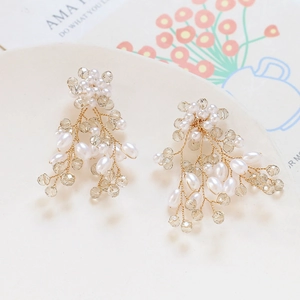 Détail de boucles d'oreilles branche faites main avec perles et cristaux en plateau