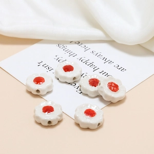 Macro shot of small ceramic flower beads with glossy red centers for DIY jewelry making