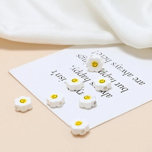 Detailed macro view of white ceramic flower beads with yellow smiley face for DIY jewelry