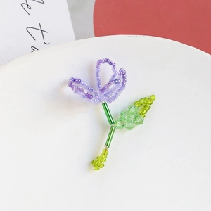 Detailed close-up of handmade beaded flower pendant with purple petals and green leaves