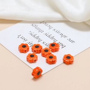 Macro shot of orange flower ceramic beads for DIY jewelry making on white silk