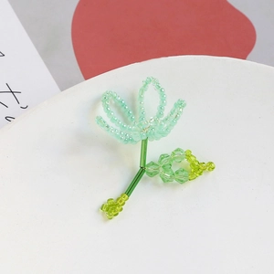 Detail of handcrafted green crystal beaded flower pendant with translucent petals and leaves