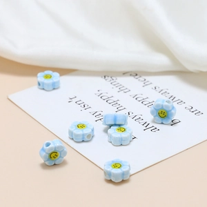 Macro shot of blue ceramic flower beads with yellow smiley faces for DIY jewelry making