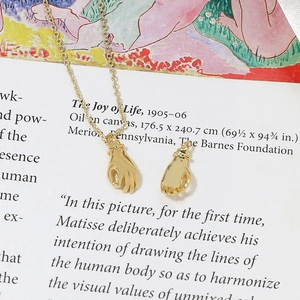 Gros plan artistique de pendentifs mains dorés et d'un collier délicat sur un livre