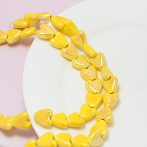 Macro shot of glossy yellow heart ceramic beads for DIY jewelry making and crafts