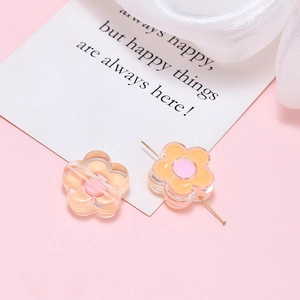Macro detail of acrylic resin flower beads for DIY crafts with metal pins on pink backdrop