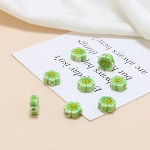 Close-up of light green ceramic flower beads with yellow smiley face for DIY jewelry