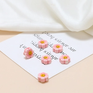 Detailed view of pink flower ceramic beads with smiley face for DIY jewelry crafting
