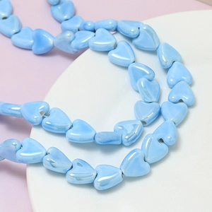 Macro detail of light blue heart-shaped ceramic beads with iridescent pearlescent finish