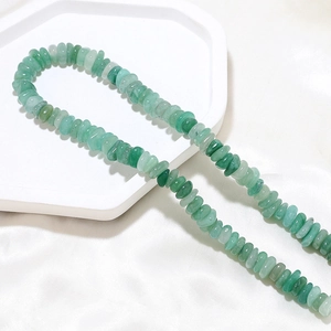 Flat natural green aventurine beads on a white tray for DIY jewelry making