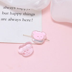 Detail of pink acrylic bear charm with metal pin on a soft decorative background