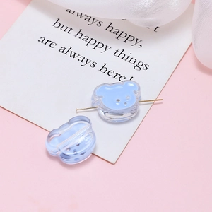 Macro view of light blue transparent bear beads with gold needle showing the drill hole