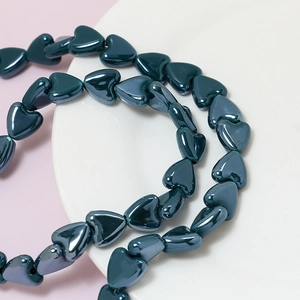 Macro detail of glossy dark green heart-shaped ceramic beads for DIY jewelry making