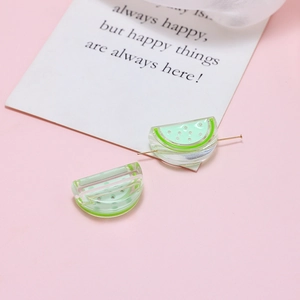 Close-up of watermelon-shaped acrylic beads with gold needle for DIY jewelry making