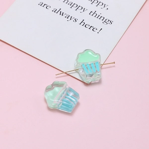 Macro shot of cupcake-shaped acrylic beads in mint green and blue for DIY jewelry crafts