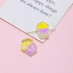 Macro detail of cupcake shaped resin beads for DIY jewelry with pink backdrop