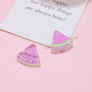 Close-up of pink resin watermelon charms for DIY jewelry making on a pink background
