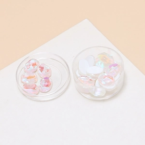 Macro view of aurora crystal glass stones in a round storage box for DIY nail art
