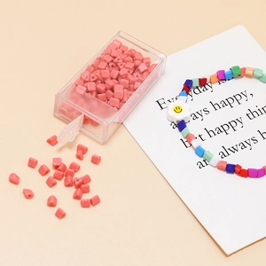 Macro shot of 4mm pink triangular beads and DIY bracelet with smiley face flower charm