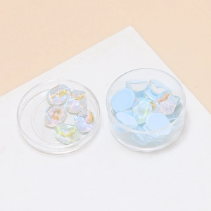 Close-up of light blue ripple jelly resin charms with pearl luster in clear plastic boxes