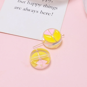 Close-up of clear resin beads with colorful abstract patterns and gold metal pin detail