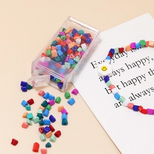 Close-up of colorful 4mm seed beads in a storage box with a flower charm bracelet