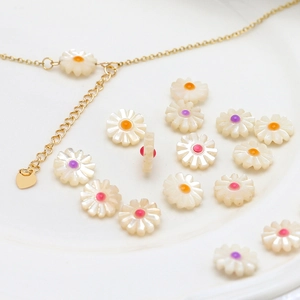Natural shell daisy flower beads for jewelry making with gold chain on ceramic plate