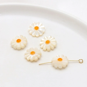 Macro shot of white daisy shell charms for DIY jewelry making on ceramic plate