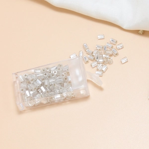 Macro shot of 4mm silver bugle glass beads for DIY jewelry making in a plastic box