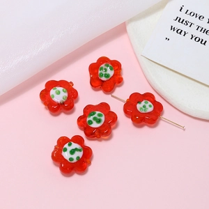 Detailed view of red glass flower beads with white and green accents for DIY jewelry making