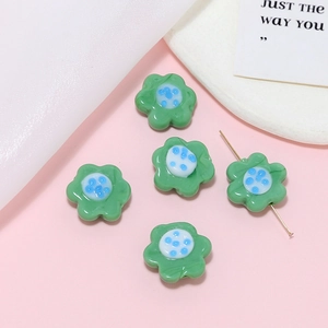 Macro shot of green glass flower beads with blue spotted centers for DIY jewelry making